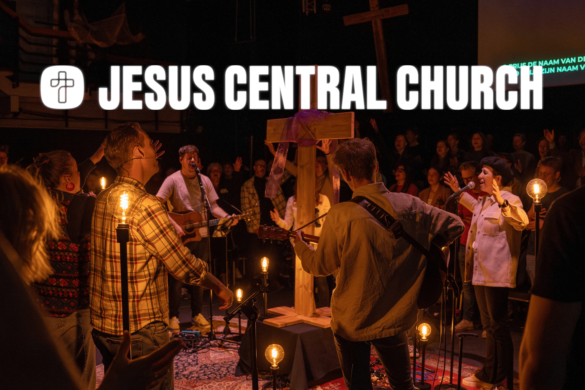 A church service with musicians and singers performing on stage, surrounded by attendees. A cross is prominently displayed in the center.